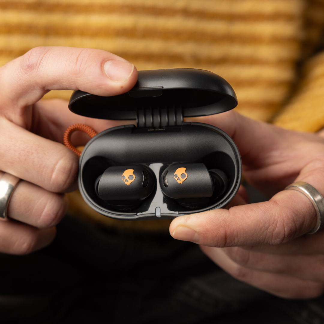 Skullcandy Sesh ANC Active - noir et orange - écouteurs rangés dans le boîtier.